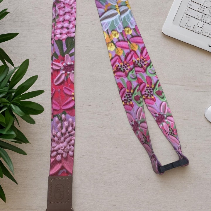Colorful floral-patterned lanyard on a light surface with a plant and keyboard in the background