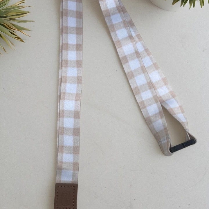 Plaid lanyard with brown leather strap and rose gold clasp on a light background
