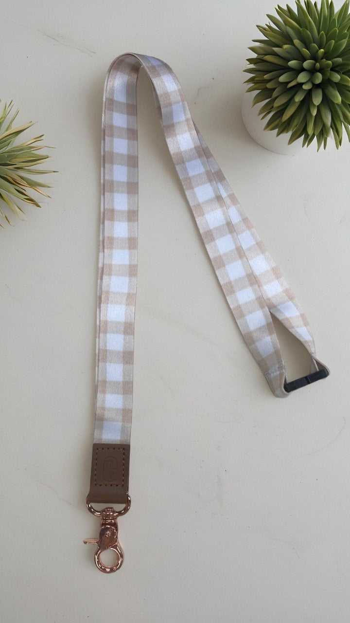 Plaid lanyard with brown leather strap and rose gold clasp on a light background