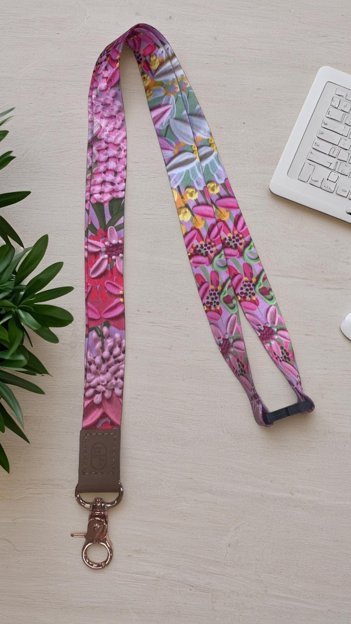 Colorful floral-patterned lanyard on a light surface with a plant and keyboard in the background
