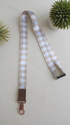 Plaid lanyard with brown leather strap and rose gold clasp on a light background